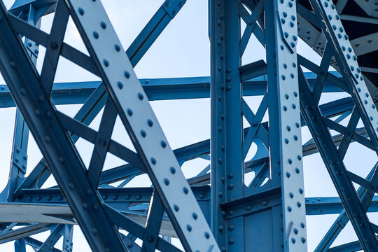 Blue steel bridge structure with rivets, arches and industrial framework closeup detailed photo