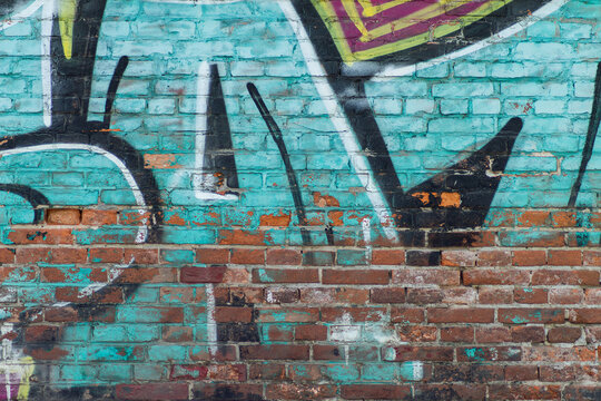 Turquoise colorful graffiti on weathered brick wall texture closeup detailed photo