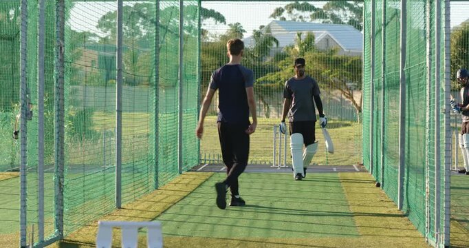 Man jogging forward, batsman leaves, bowling red ball toward next batsman in practice net