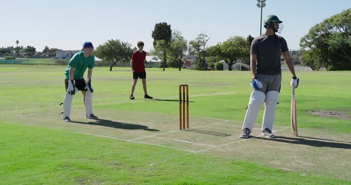 White teenage wicketkeeper diving snatching edged ball on pitch, delivery team celebrating
