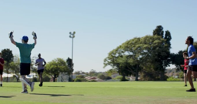 Teenage male player wicketkeeper lunging for ball making run-out, running to cheering teammates