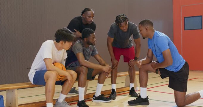 Hearing coach's talk basketball team stacking hands and cheering on bench for game start