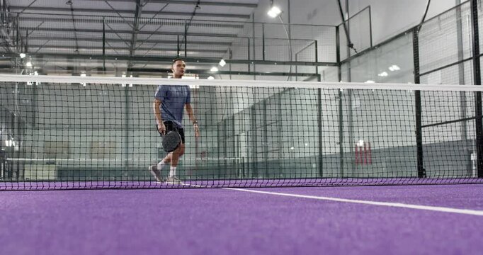 Two male rivals shifting after yellow ball flying toward net volleying with paddles on court
