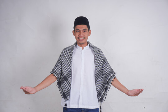 Young smiling happy Asian Muslim man in Arab costume kifaya, pecis with praying gesture facing upwards isolated on white background. Muslim people