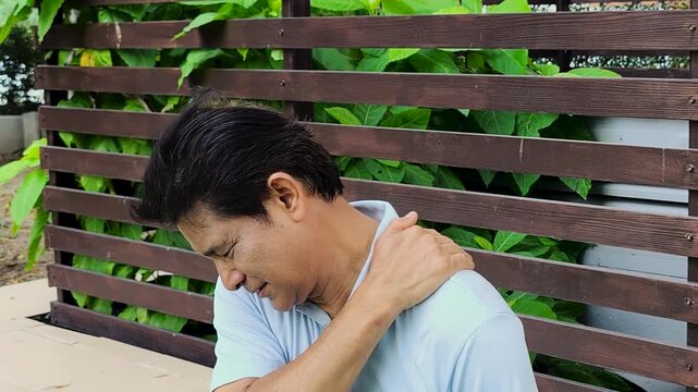 Middle aged asian man suffering from shoulder pain, shoulder injury, shoulder stiffness symptoms  with office syndrome or overwork