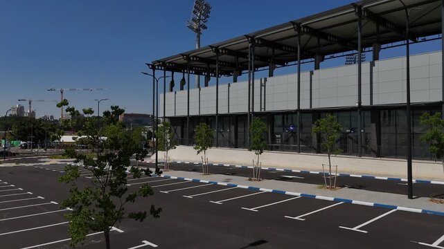 4K slow motion drone vertical ascent from ground level revealing corner of new stadium in Rehovot and expanding view of industrial park and urban landscape in Israel cinematic aerial rise shot