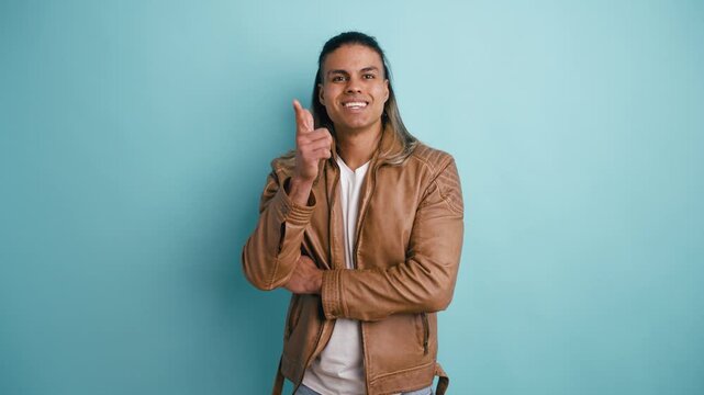 Handsome latino man thinking about a problem, then having an eureka moment and smiling. He points to the camera, sharing his brilliant idea