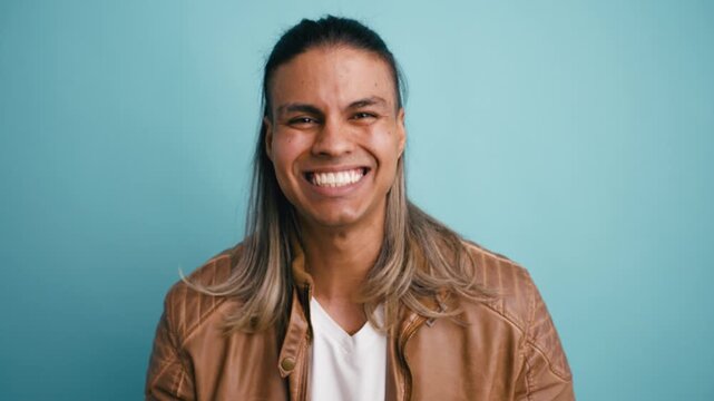 Expressive man looking at the camera with a big smile, showing gestures of approval and excitement against a solid turquoise background