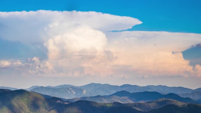 Dangerous clouds scatter across the sky from a explosion in the depths of the Rhodope Mountains with spruce forests, meadows and villages