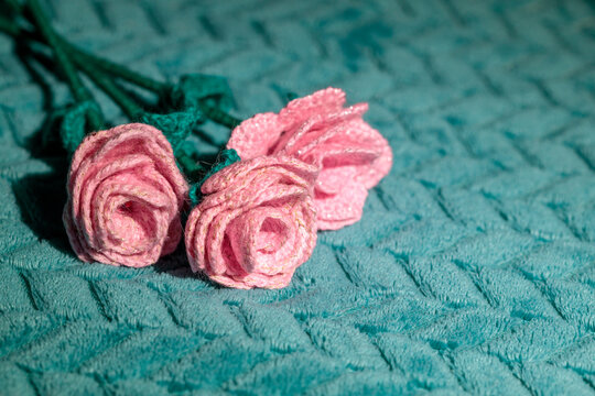 Trio of textile pink roses against green cloth surface