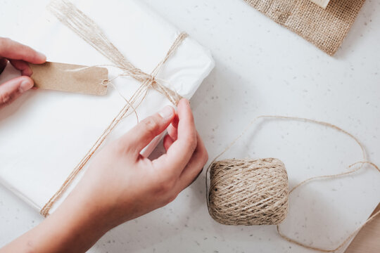 Close up of person hands wrapping gift box with rustic twine wrapping packaging handmade creative workshop birthday