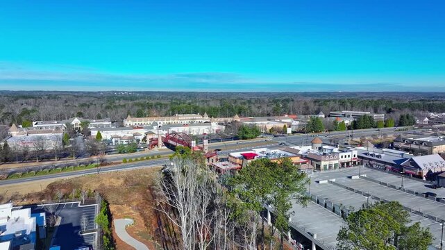 Revealing The Peachtree Corners pedestrian bridge with The Forum Peachtree Corners shopping mall in background, Peachtree Parkway (SR 141) in Georgia, drone shot