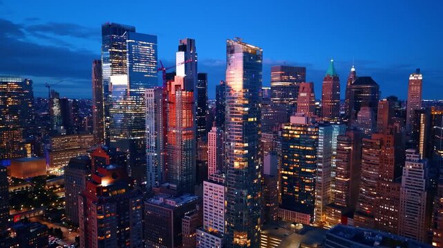 Stunning glossy high-rises reflecting the city lights. Drone flight among the gorgeous buildings of New York City at dusk time.