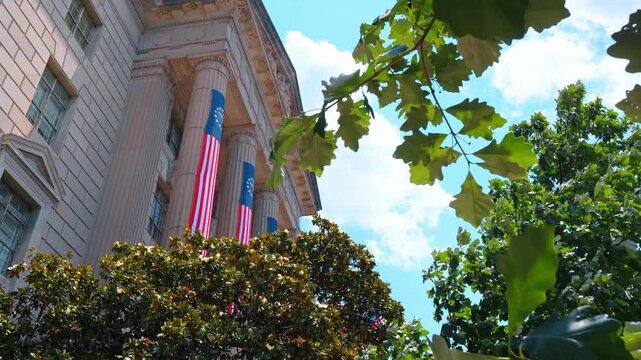 Robert F. Kennedy Department of Justice Building, located in Washington, D.C. Low angle view at the facade with columns and flags on.