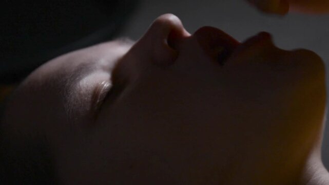 Top view close up of a young woman lying on her back and stuffing her mouth with large amounts of popcorn while watching a movie. 