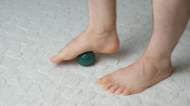 Man massaging myofascial trigger points on foot with green spiky ball