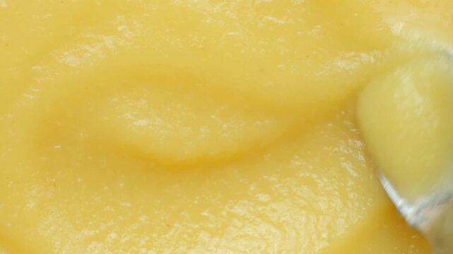 Macro video of smooth apple sauce texture with swirling motion.