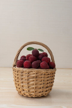 Fresh red bayberries in a rustic wicker basket on a wooden table