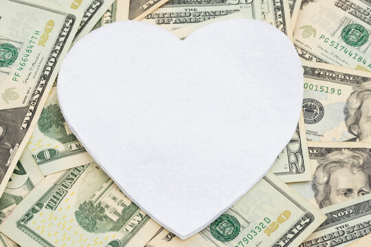 Blank white heart on twenty dollar bills for cost of relationships