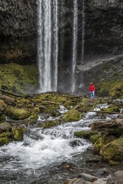 Hiker in front of a high waterfall, water falls over a rocky outcrop, Tamanawas Falls, Wild River Cold Spring Creek, Oregon, USA