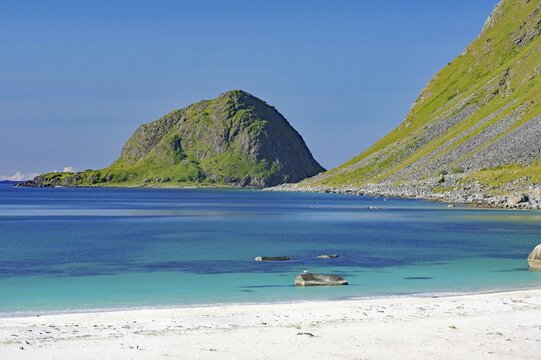 A secluded beach borders a crystal clear sea against a mountain backdrop, Haukland, Leknes, Vestv&aring;g&oslash;ya, Lofoten, Nordland, Norway