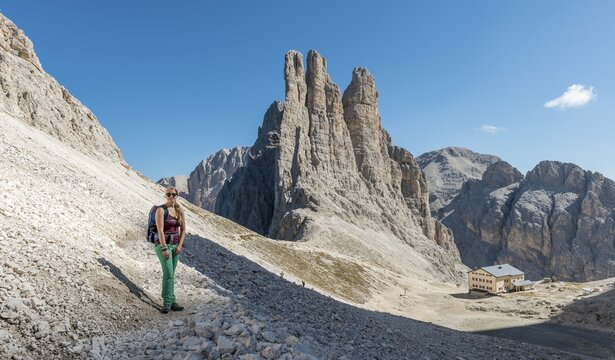 Hiker on the descent from the Santner via ferrata, in front Gartl hut, at the back cliffs Vajolett towers, Rosengarten group, Dolomites, UNESCO World Heritage Site, Alps, South Tyrol, Trentino-Alto Adige, Italy