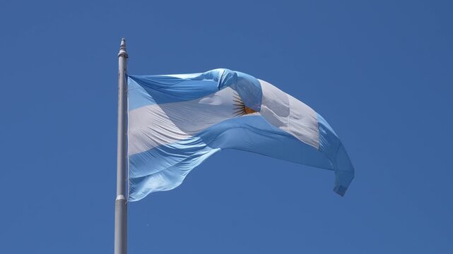 Argentine flag with the sun of may symbol slowly waving on a flagpole. National patriotism and pride concept against a clear blue sky