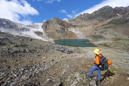 Mountaineer in front of mountain landscape with limestone rocks between granite mountains, mountain lake Hinterer Senner Egetsee and mountain peak of the Moarer Wei&szlig;en, Seven Lakes Hike, Stubai Alps, near Ridnaun, South Tyrol, Italy