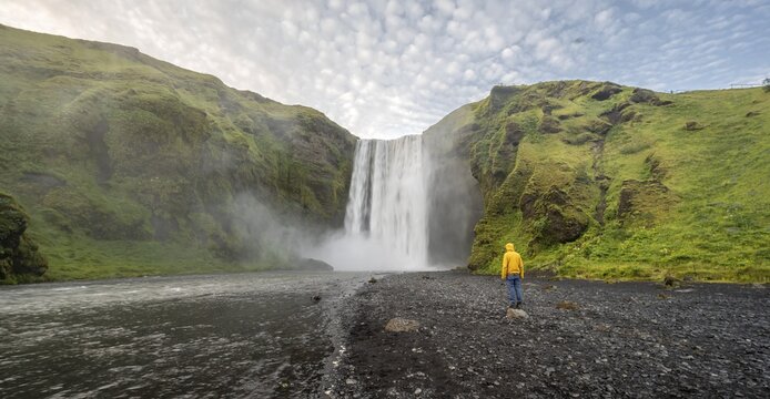Huge waterfall behind a person, Sk&oacute;gafoss waterfall, South Iceland, Iceland