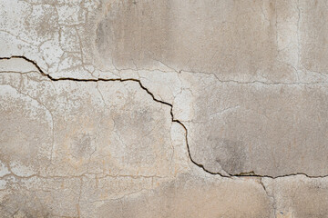Fototapeta premium Deep diagonal crack on old concrete wall background. Grunge textured cement surface showing damage, fracture and aging structure. Perfect for renovation, insurance or risk concept backdrop