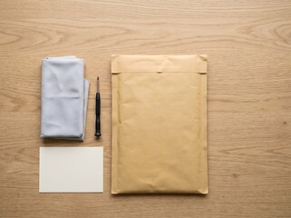 Fototapeta premium A clean top-down mail-in repair kit with a padded envelope, small device wrapped in cloth, blank return card, and pen for electronics repair, product return, and sustainable device care.