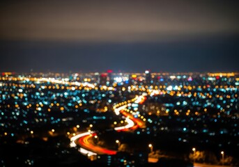 Fototapeta premium Blurred night cityscape with glowing orange traffic light trails and blue urban bokeh lights