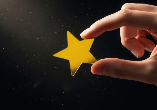 Hand holding a bright yellow star shape against a dark background, with floating dust particles