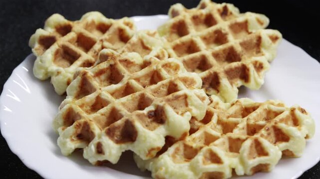 Stack of fresh homemade Belgian waffles served on a minimal white plate