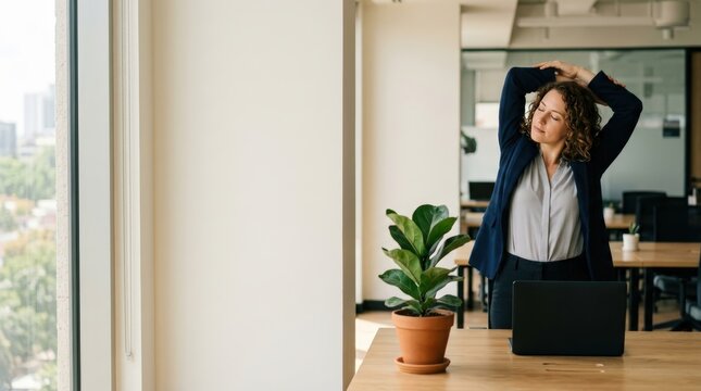 Businesswoman stretching shoulders beside desk in modern office