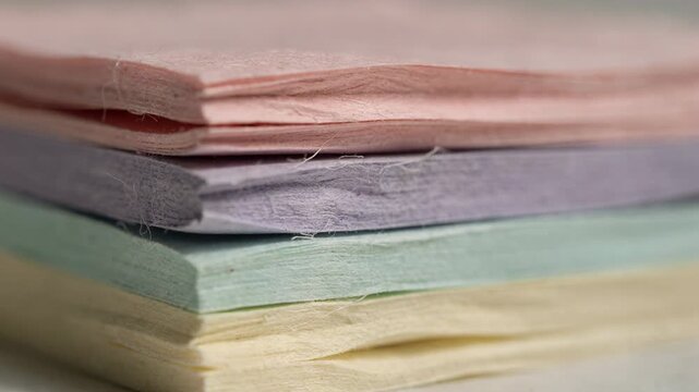Closeup of pastel sticky note blocks undergoing compression highlighting soft muted tones and delicate textures for creative journaling.
