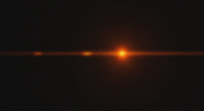 Abstract glowing orange light beam with lens flare on black background for technology and sci-fi design