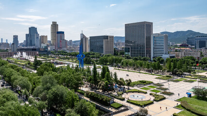 Naklejka premium Urban Square with Modern Buildings and Green Spaces Under Clear Sky