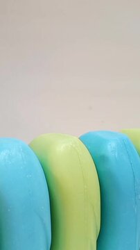 Soap bar. blue and yellow soap bars for bath in a row rotating on white background. aromatic soap for body and face. pieces of blue and yellow bathing soap. vertical clip