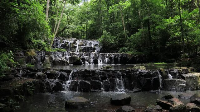 The video background features a natural landscape of a waterfall in a lush forest. Sam Lan Waterfall in Saraburi National Park boasts beautiful flowing water surrounded by diverse flora.