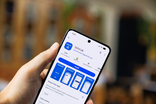 Close-up of a hand holding a smartphone displaying the GOV UK app interface on Google Play Store