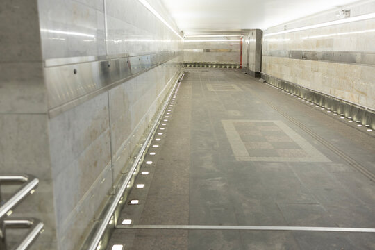 Empty modern pedestrian underpass with marble walls and bright line lighting