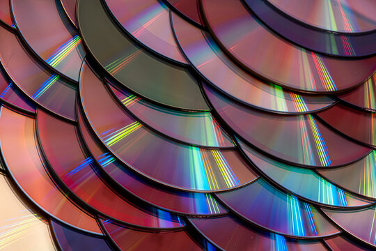 a dense, overlapping pattern of compact discs with rainbow light reflection arranged like fish scales