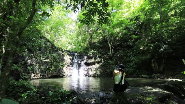 The video background features a natural landscape of a waterfall in a lush forest. Sam Lan Waterfall in Saraburi National Park boasts beautiful flowing water surrounded by diverse flora.