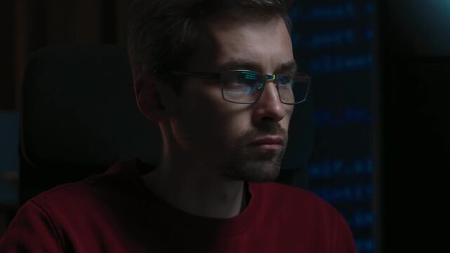 Male coder typing programming script on a keyboard late at night, code reflecting in his glasses. Developer works from a dark home office, concentrated on debugging