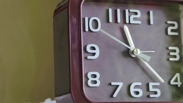 Smooth panning macro shot across the face of a brown analog clock with white numbers. The steady pace of the second hand illustrates concepts of timekeeping and patience.