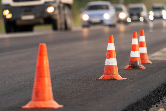 Road repair and new asphalt paving on highway with closed traffic lane, roadworks, vehicles in traffic flow and temporary traffic restrictions