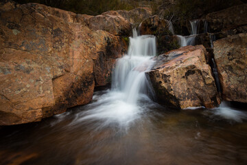 Obraz premium Cascading waterfall over red rock formations