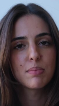 Emotional young woman's face singing a song in a close-up shot, with her eyes closed in concentration, expressing deep feelings and passion while enjoying the music