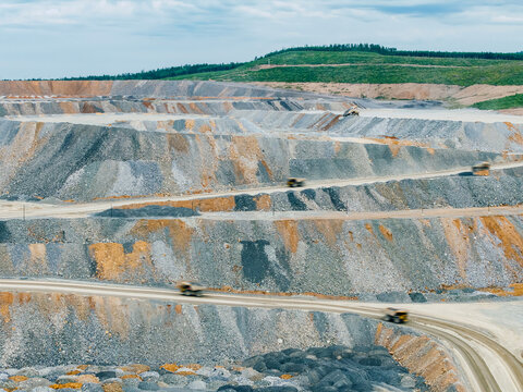 Open pit mine haul trucks driving along winding mine terraces